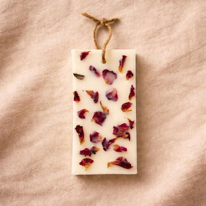 Rectangular soap bar with dried flowers on a beige fabric background
