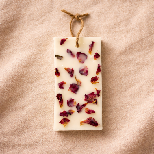 Rectangular soap bar with dried flowers on a beige fabric background