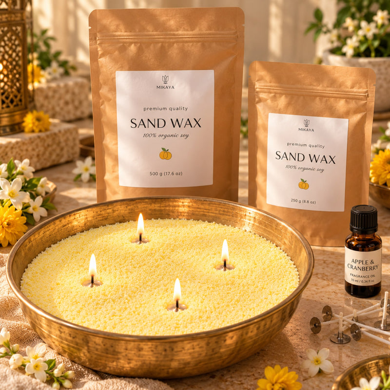 Yellow sand wax candle in a brass urli with four lit wicks, beside 250 g and 500 g Mikaya sand wax pouches, fragrance oil and wicks