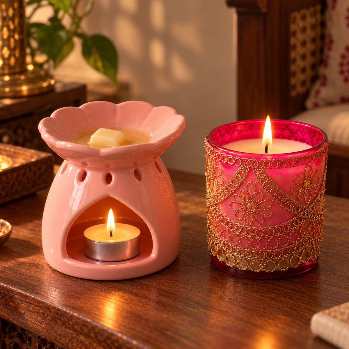 Pink Dahlia wax melter warming a Vanora wax melt with a tealight, beside a lit Chandni jar candle with gold zari work