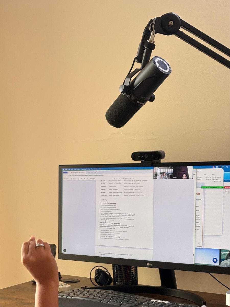 A monitor showing course notes on a live video call, with a microphone and camera above the desk