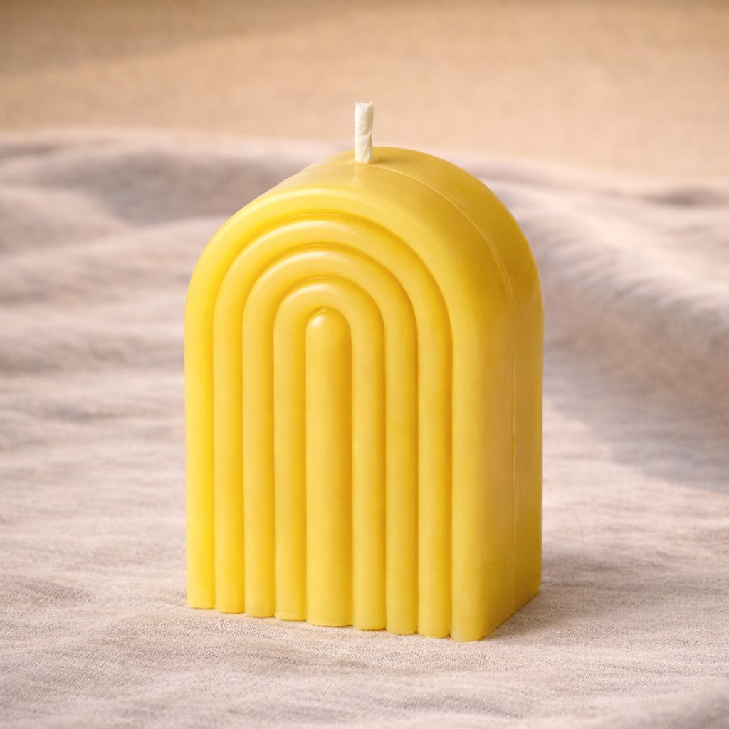 A yellow arch shaped sculptural candle with ridged lines, an example of a moulded candle taught in the course
